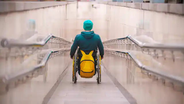 person in wheelchair travels down long ramp