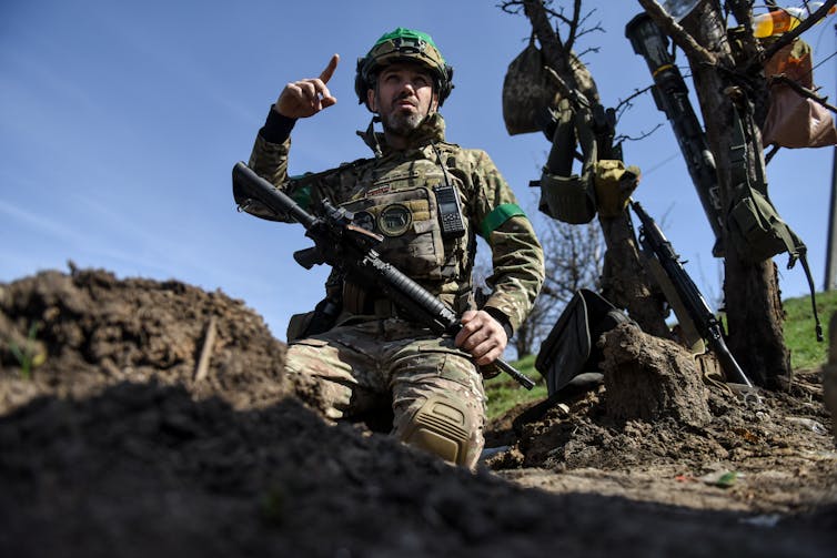 A Ukrainian soldier points to the sky from a trench outside Bakhmut, eastern Ukraine.