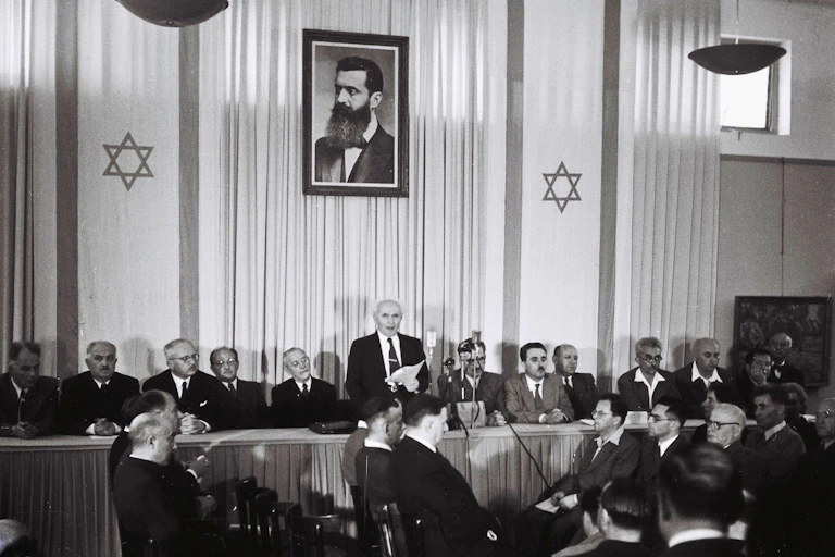 David Ben-Gurion declaring independence beneath a large portrait of Theodor Herzl, founder of modern Zionism