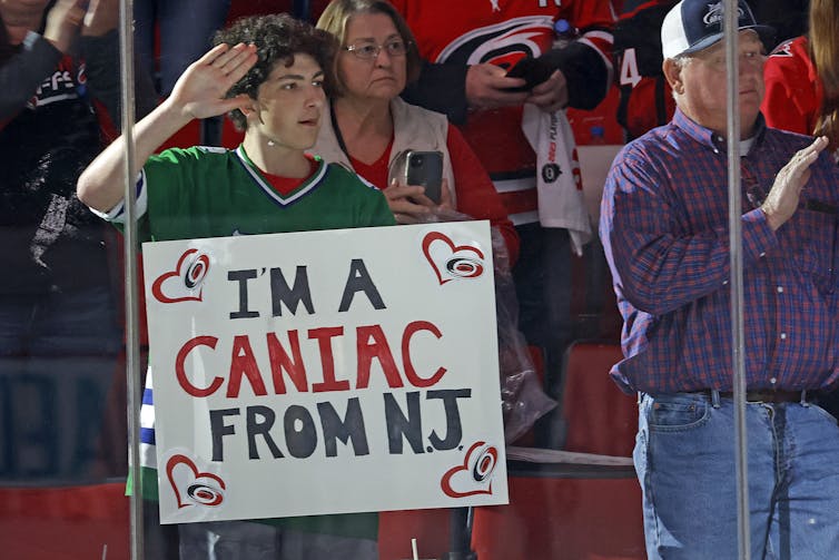 a man in the stands holds a sign reading I'M A CANIAC FROM N.J.