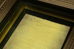 A document is seen under glass in a display case.