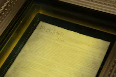 A document is seen under glass in a display case.