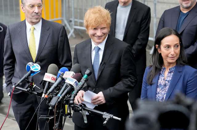 Singer Ed Sheeran standing outside a NY court with his lawyers making a statement.