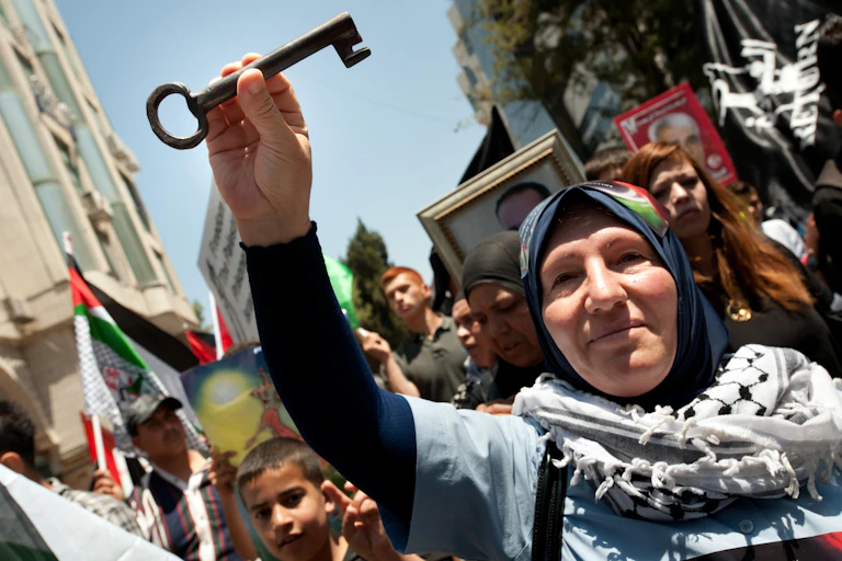 A woman on a busy street holds a key in the air.