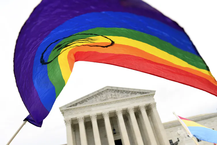 rainbow flag is seen with the supreme court's columned building in background