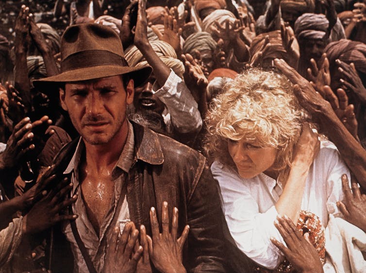 Indiana Jones and partner surrounded by the outstretched hands of local Indian people.