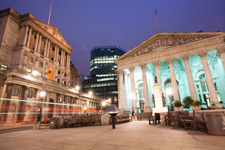 Two buildings with columns, night sky, moving traffic.