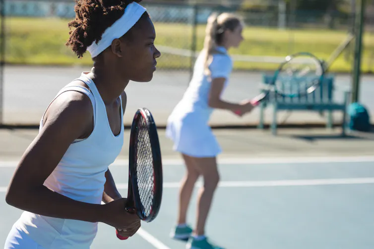 Two women playing doubles tennis