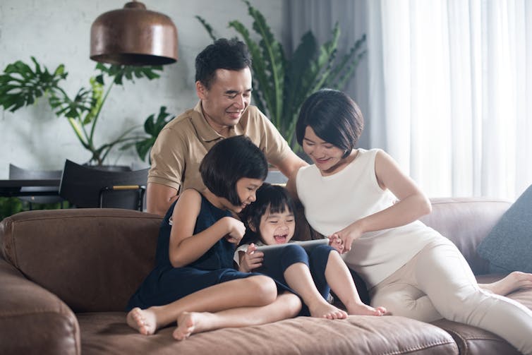 A family on a sofa looking at a tablet.