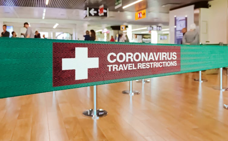 a sign at an airport that reads: Coronavirus travel restrictions.