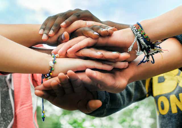 Several pairs of multi-racial hands holding each other