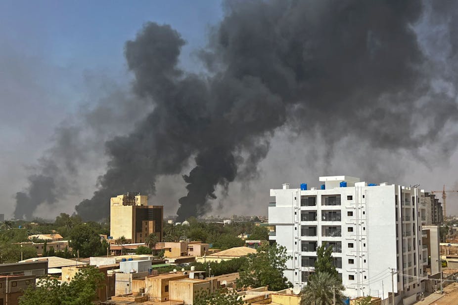 A black plume of smoke rising above residential buildings.