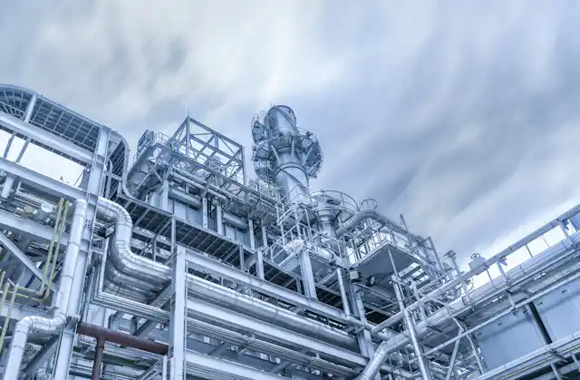 Silver tubes of a gas power plant with a gray sky with clouds.