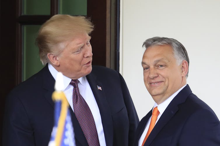 Two men in suits shake hands.