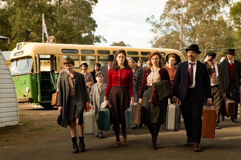 People with suitcases walk off a bus
