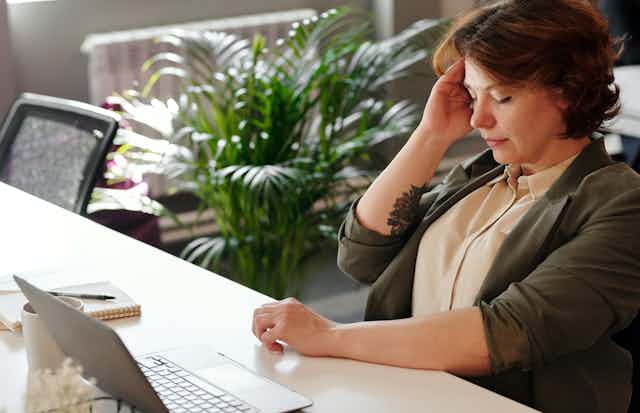 Middle-aged woman at her desk has a headache