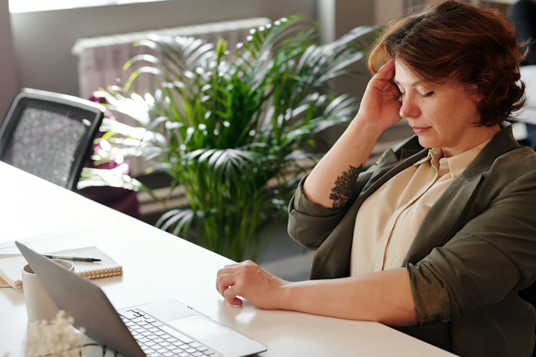 Middle-aged woman at her desk has a headache
