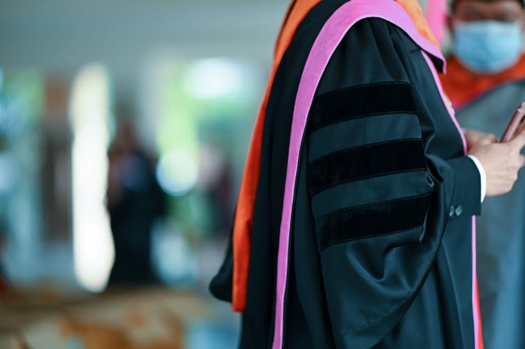 A PhD graduate in a graduation gown.
