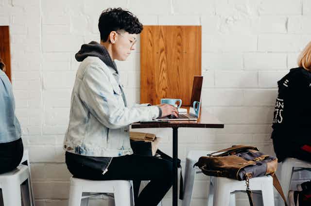 A student sits at a table, working on a computer.