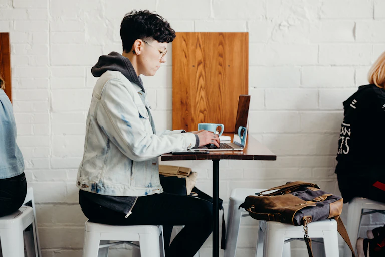 A student sits at a table, working on a computer.
