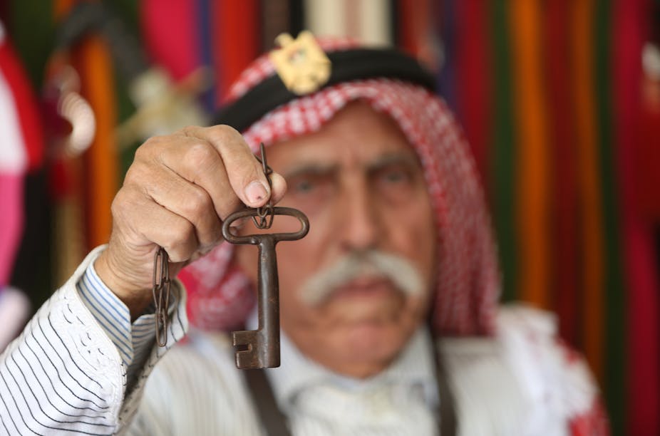 An Arab man holds up a large key.