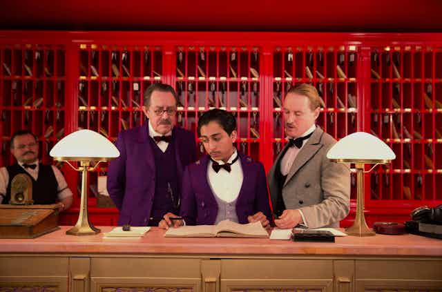Three men behind a hotel check-in desk