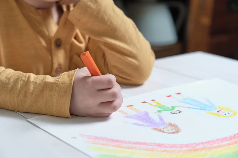 Child drawing rainbow and family