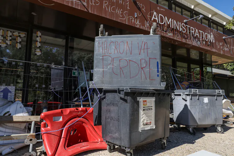 Le 4 avril 2023, l’entrée d’un bâtiment de l’université Paul Valery à Montpellier bloquée par des tables, des chaises et des poubelles pour protester contre la réforme des retraites, un slogan « Macron va perdre » est inscrit