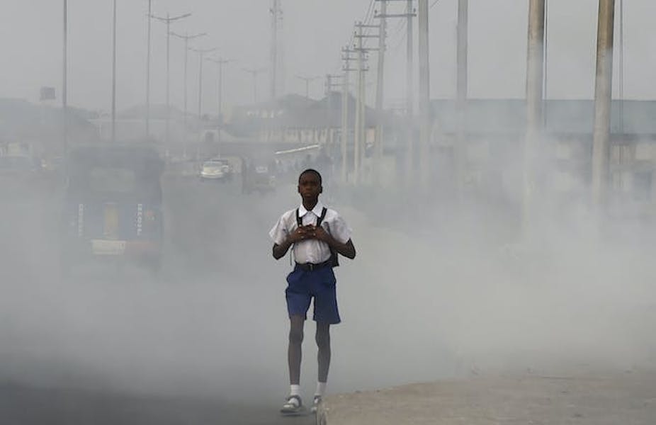 Un garçon portant un sac à dos marchant dans une rue couverte de fumée.