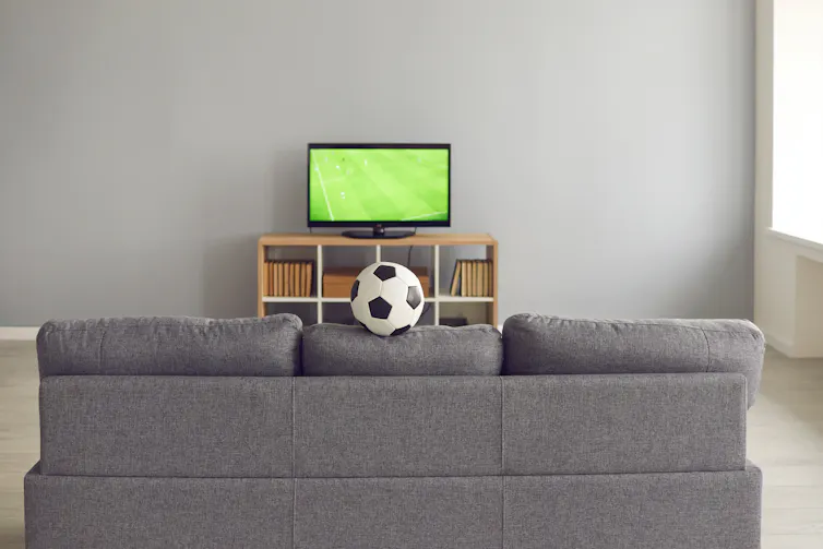 TV showing football in front of a sofa.