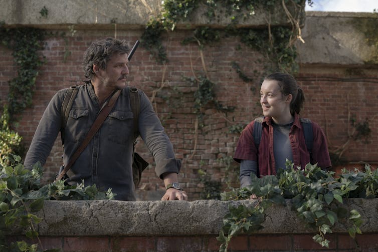 Pedro Pascal and Bella Ramsey smile at each other.