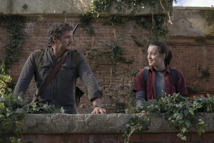Pedro Pascal and Bella Ramsey smile at each other.
