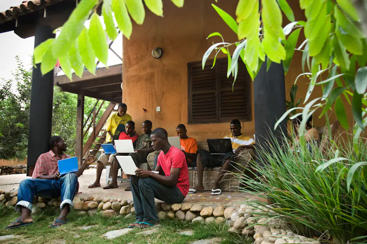 An exterior shot of a building with people working on laptops.