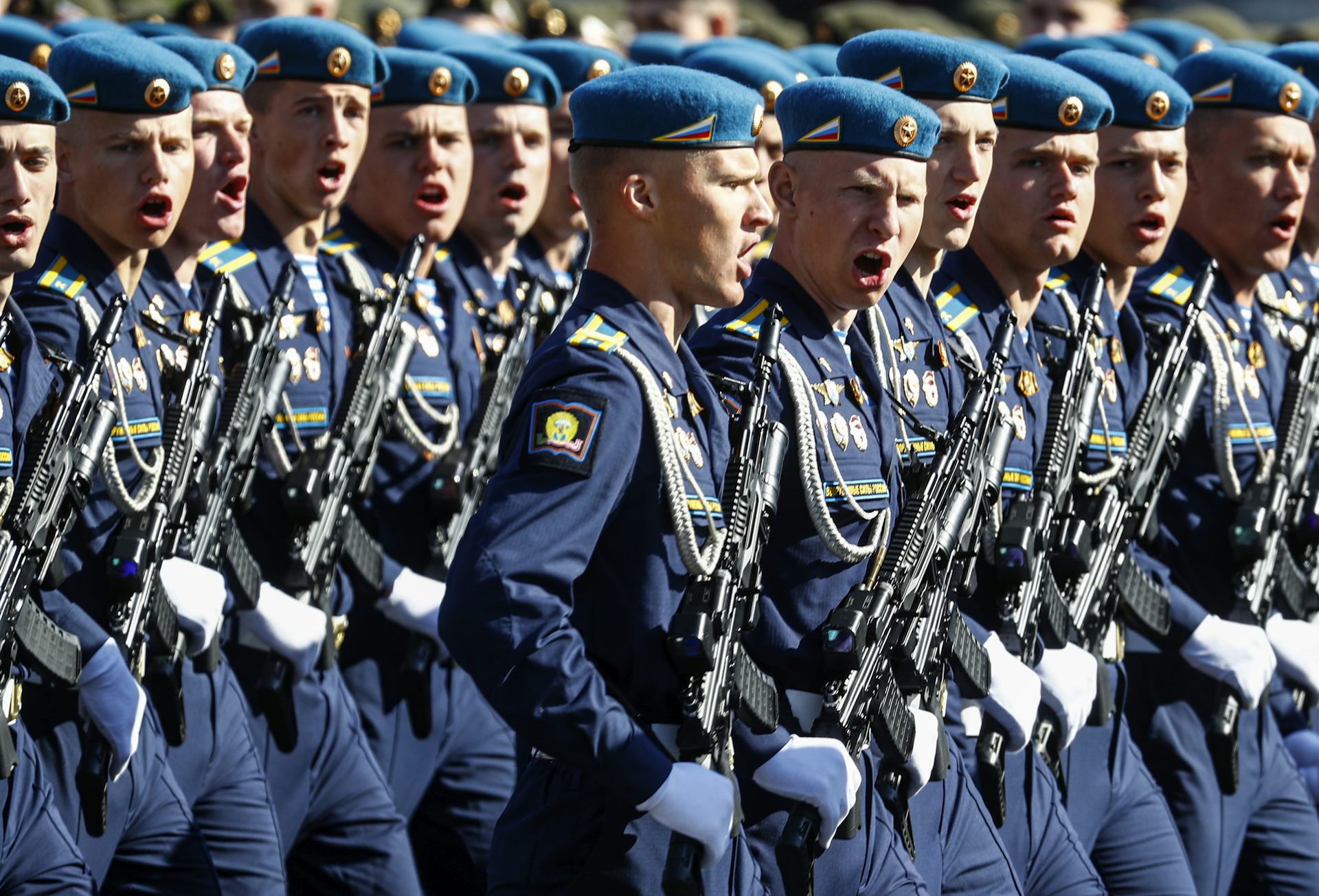 Russian soldiers in formation, carrying rifles and shouting.