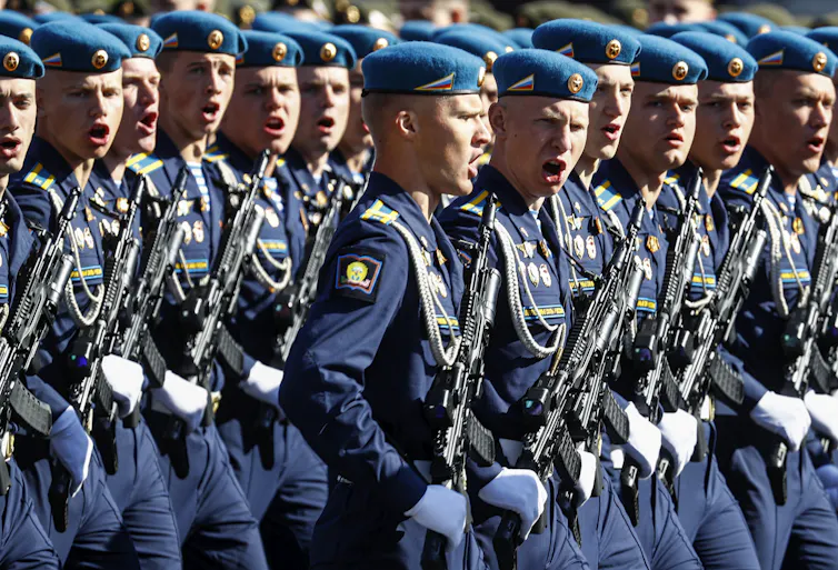 Russian soldiers in formation, carrying rifles and shouting.