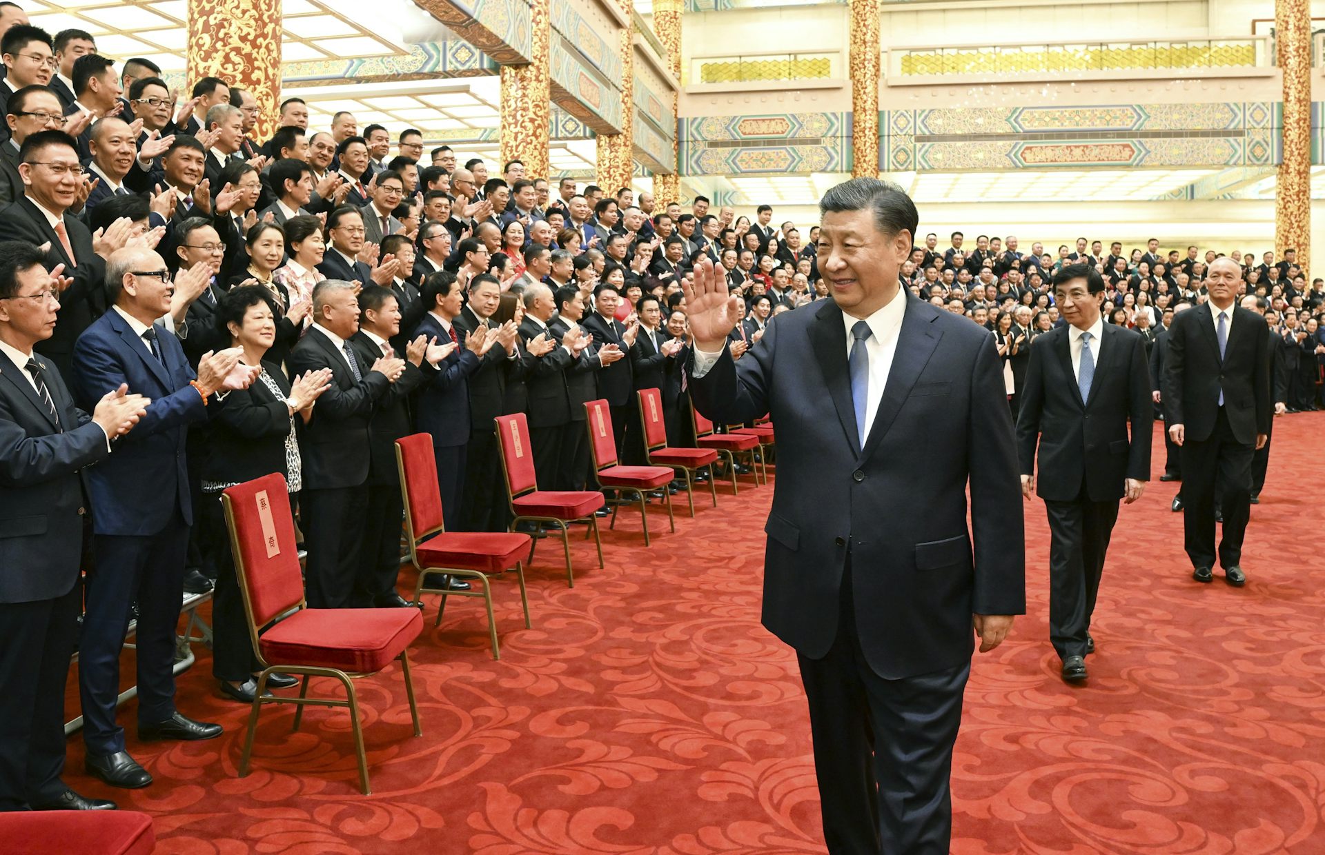 Chinese president Xi Jinping walks through a large room greeting Chinese and foreign dignitaries.