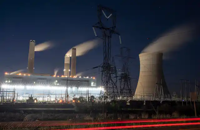Steam blows away from power plants smokestacks and a cooling tower
