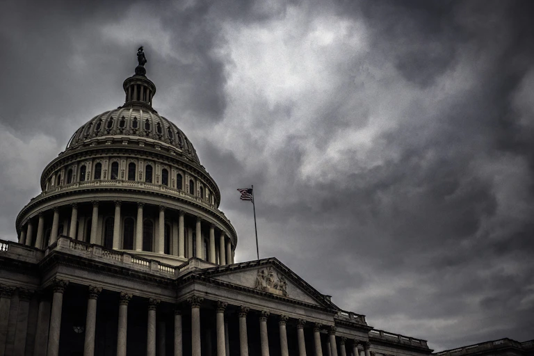 A large white building with a dome, set against dark clouds.