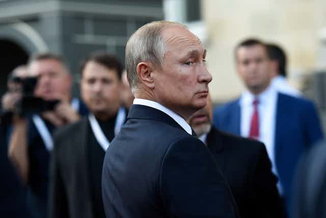 Russian president Vladimir Putin looks over his shoulder