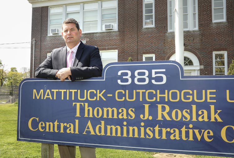 A man dressed in a business suit stands outside of a building.