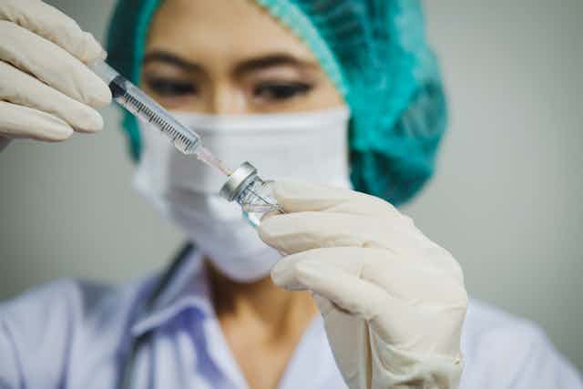 A nurse draws up a vaccine.
