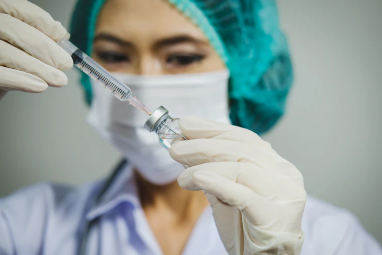 A nurse draws up a vaccine.