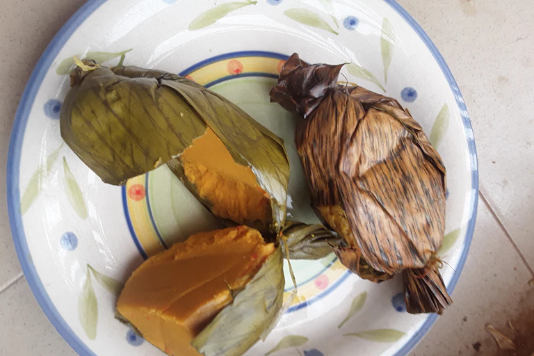 Food wrapped in leaves on a plate.