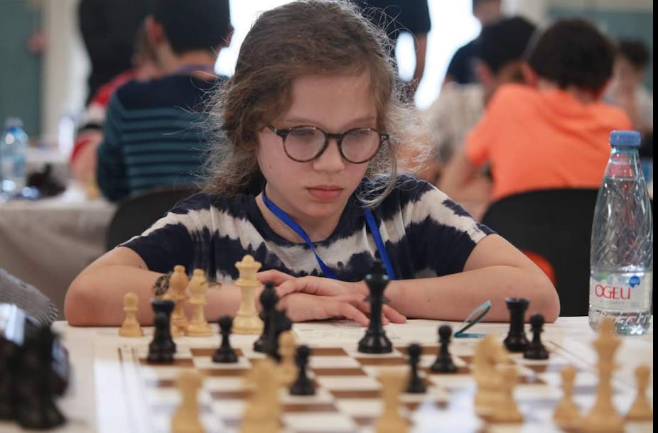 Une fillette devant un échiquier pendant un tournoi