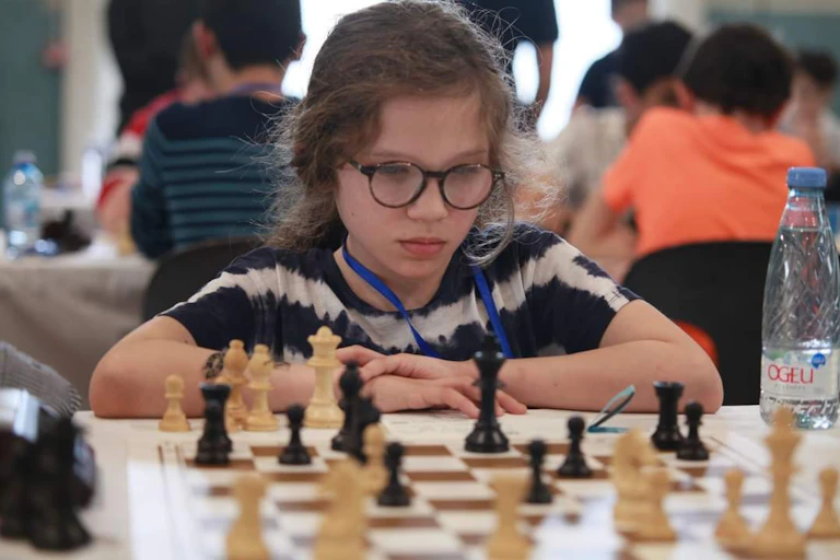 Une fillette devant un échiquier pendant un tournoi