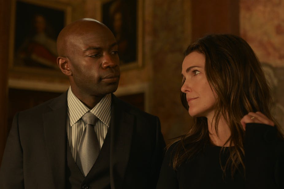 David Gyasi in a suit and Keri Russell all in black, gazing at each other. 