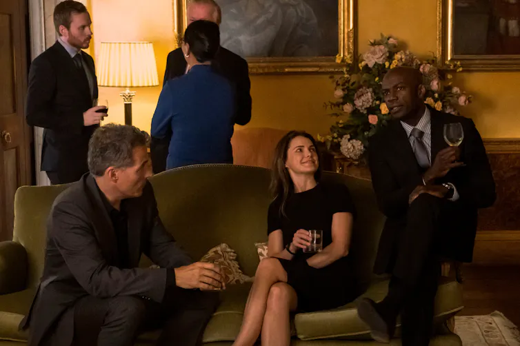 Rufus Sewell as Hal Wyler, Keri Russell as Kate Wyler, David Gyasi as Austin Dennison sitting in a reception room drinking wine.