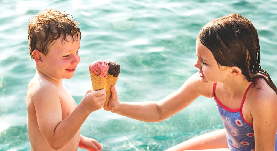 Deux enfants mangent de la glace dans une piscine, il fait chaud