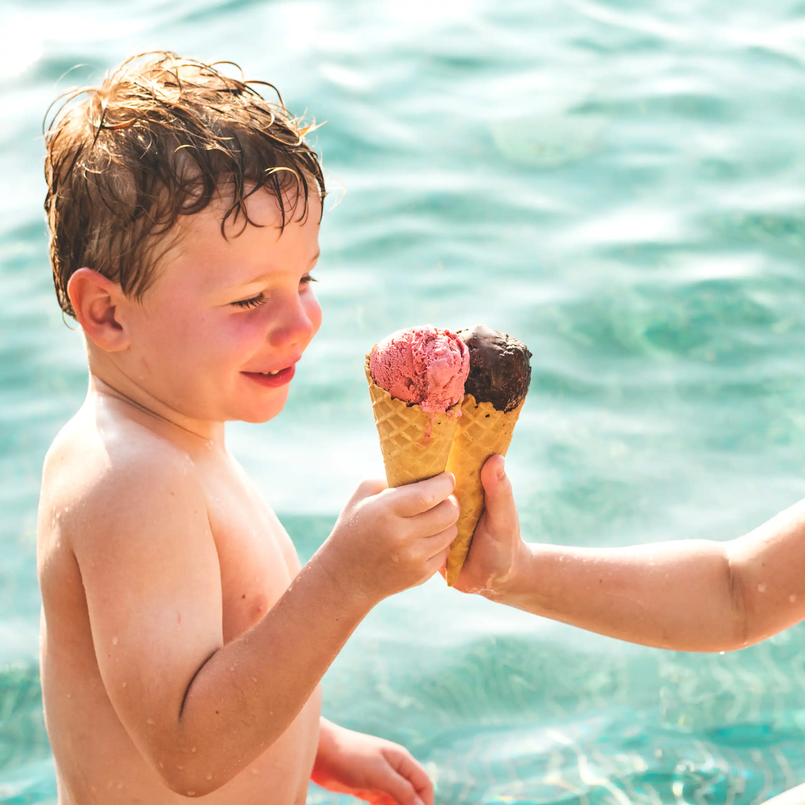 Deux enfants mangent de la glace dans une piscine, il fait chaud