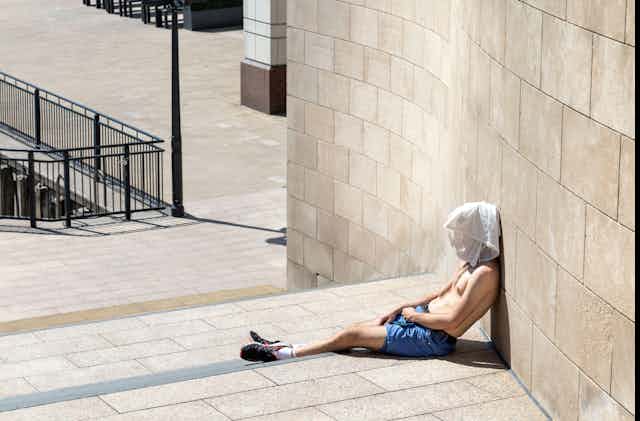Topless man with a T-shirt over his head during London heatwave in Canary Wharf, London.